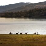 , a group of people riding horses across a field
