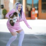 Bimbo girl tripping., a woman in a pink dress holding a dog